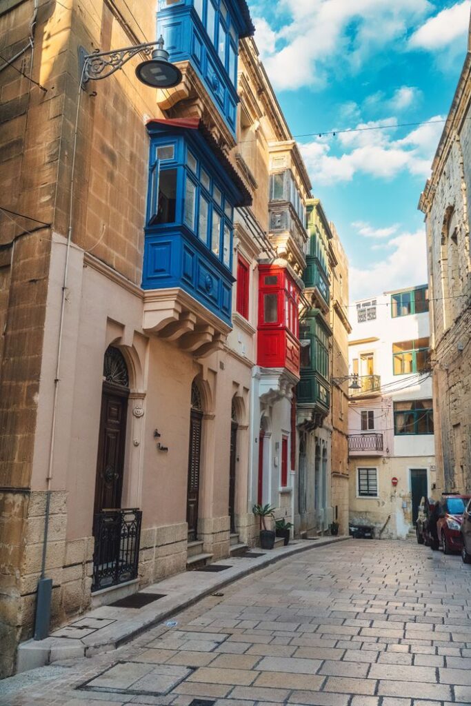 Vibrant street view with colorful balconies in Malta, showcasing traditional architecture.