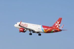 Air Malta jet flying smoothly against a blue sky, showcasing vibrant tail design.