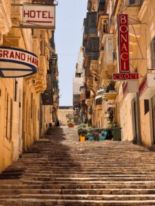 Picturesque view of a sunny, narrow street in Valletta with local shops.