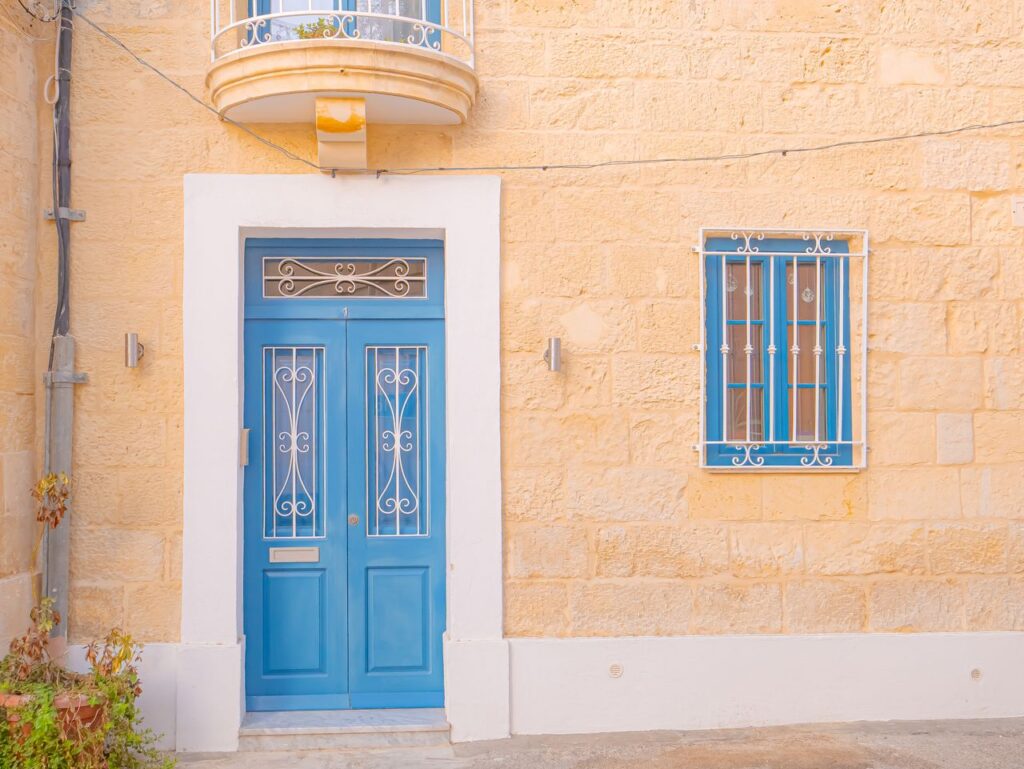 A vibrant blue door on a limestone facade featuring Mediterranean architecture.