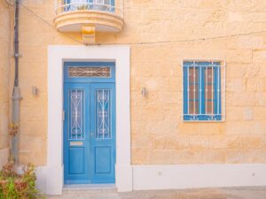A vibrant blue door on a limestone facade featuring Mediterranean architecture.