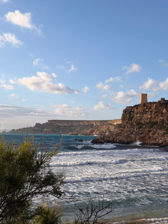 Breathtaking coastal view of Għajn Tuffieħa with rugged cliffs and tower under a bright sky in Malta.