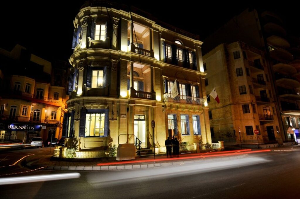 Beautifully lit historic building on a street corner in Sliema, Malta at night.